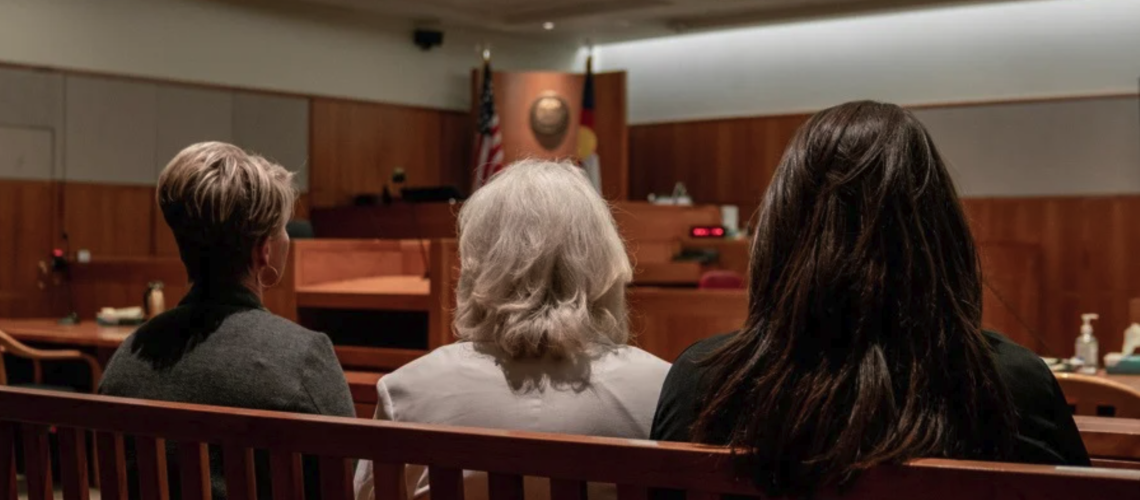 Three women sitting in a courtroom pew, facing the front — symbolizing presence, support, and trauma healing during legal proceedings.